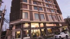 A multi-story hotel with a modern design, featuring a prominent orange accent on the upper floors, large windows, and a visible entrance with a bicycle parked outside. - Hive Hotel and Convention Place (Quezon City)
