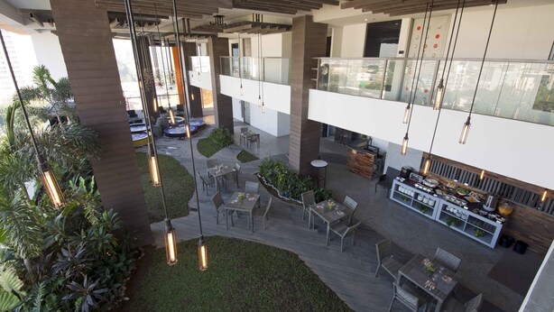 A spacious outdoor area with multiple seating arrangements, including tables and chairs, surrounded by greenery and modern lighting fixtures. - Hive Hotel and Convention Place (Quezon City)