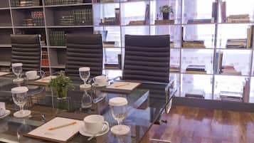 Una sala de conferencias con una mesa de vidrio, sillas y una estantería llena de libros.