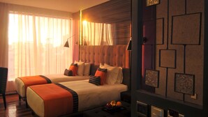 A hotel room with two beds, a desk, and a chair. There are curtains, a lamp, and a wall with square decorations. - Hive Hotel and Convention Place (Quezon City)