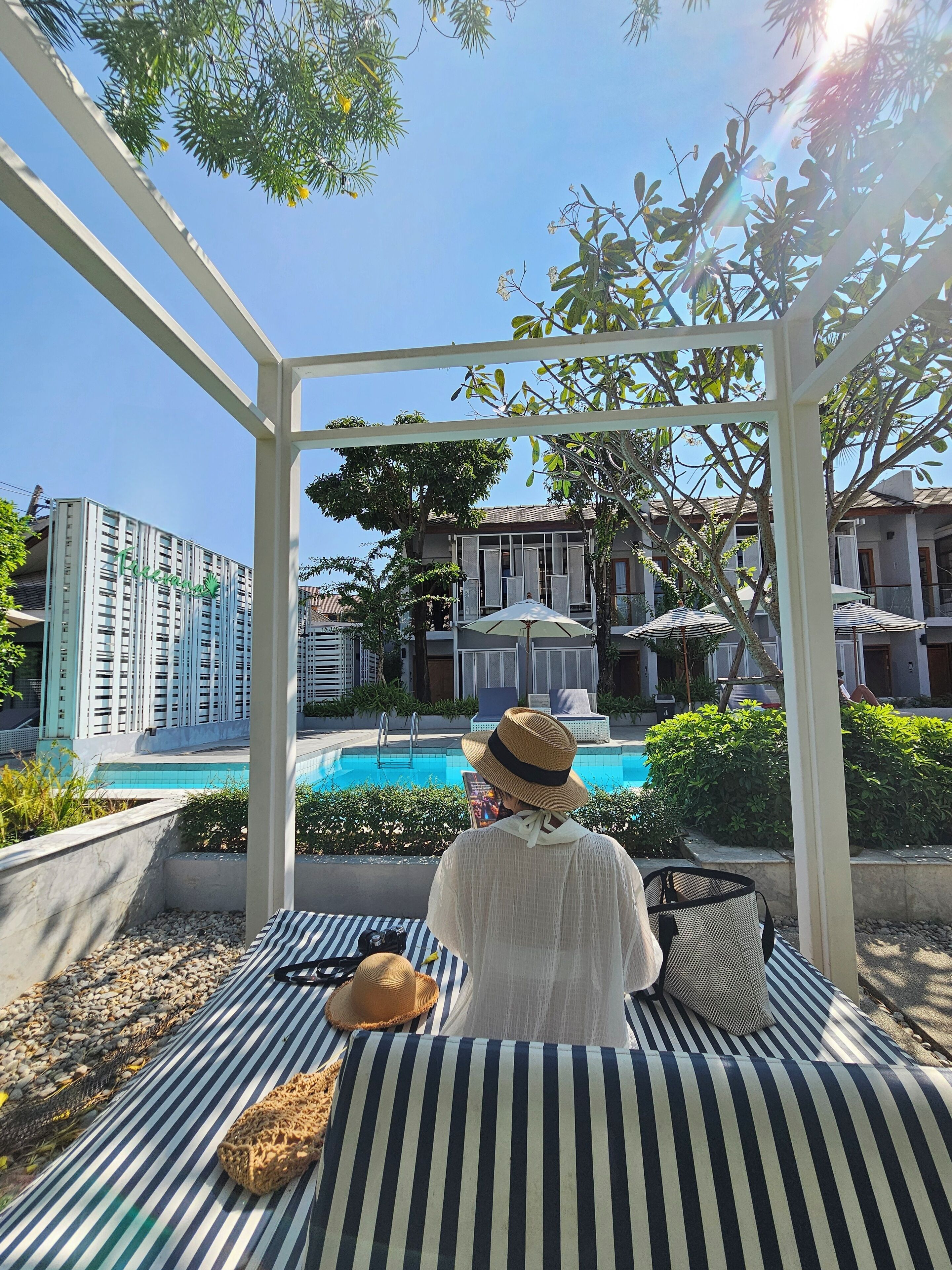 A person relaxing on a striped lounge chair by a pool, with a building labeled 'Crescent' in the background.