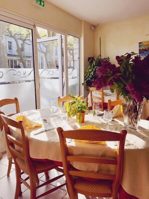 A dining area with round tables, chairs, and a potted plant. - Hotel de la Montagne Noire (Dourgne)