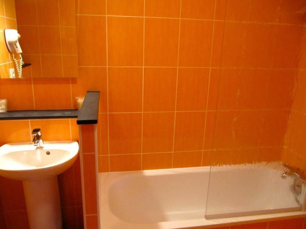 Ein Badezimmer mit orangefarbenen Fliesen, einem weißen Waschbecken und einer Badewanne.