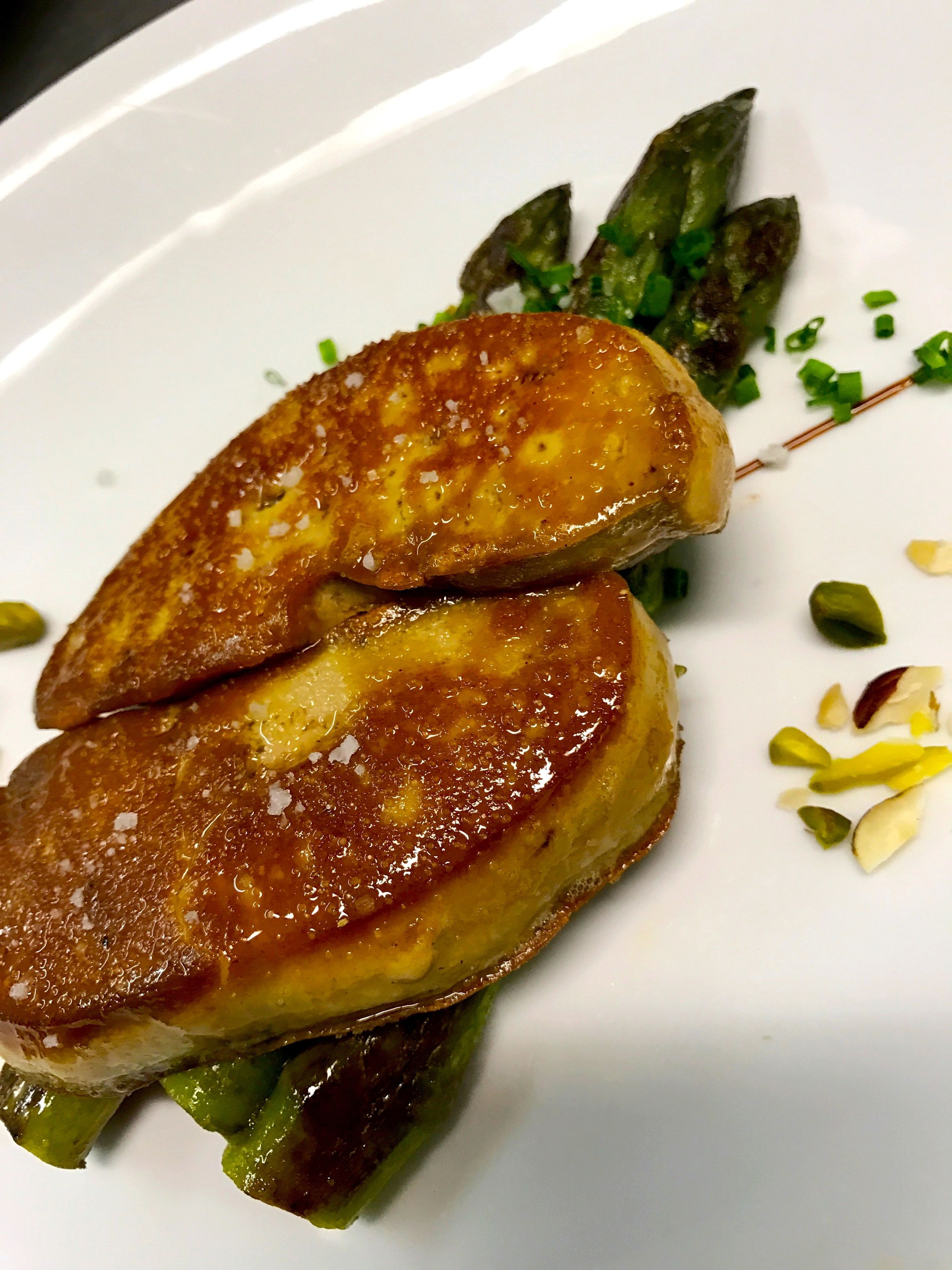 Un plato con dos tortitas doradas, espárragos verdes y hierbas verdes picadas.