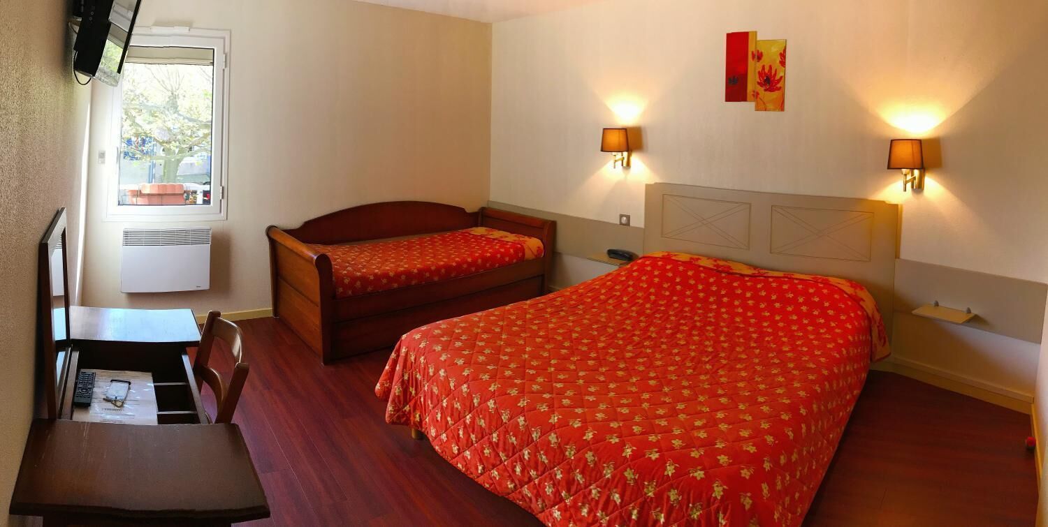 Ein Hotelzimmer mit zwei Betten, einem Schreibtisch, einem Stuhl, einem Fenster und zwei Wandleuchten.