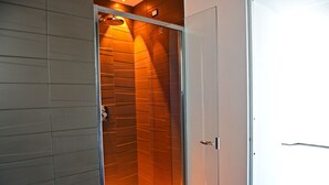 Een moderne badkamer met een douchecabine van glas en een witte deur.