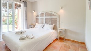Un dormitorio con una cama grande, una mesita de noche, una ventana con cortinas y vistas al exterior.