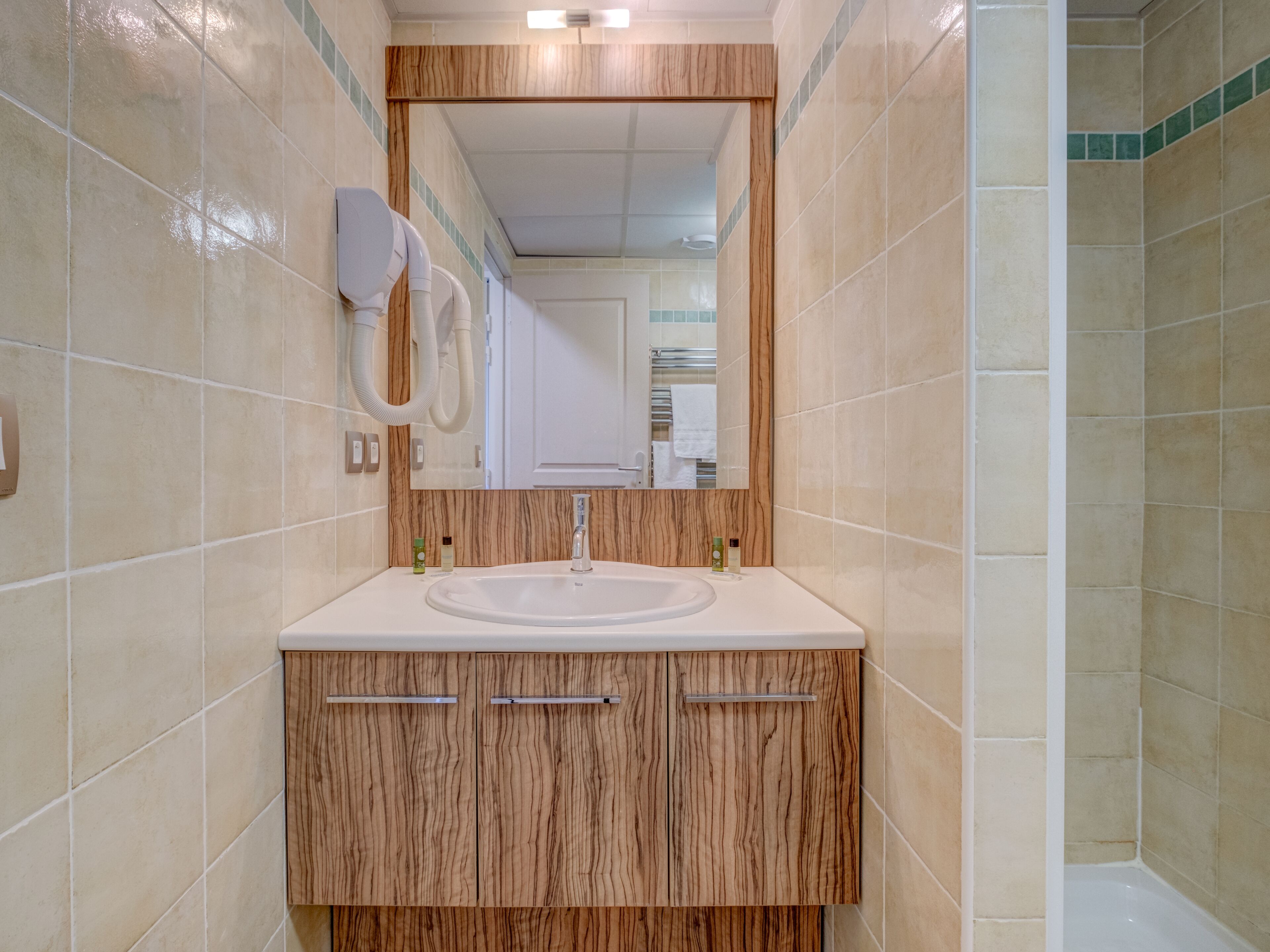 A bathroom with a sink, mirror, and wooden cabinets.