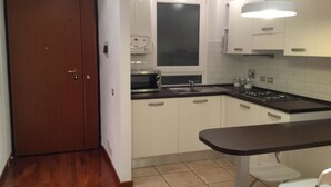 A kitchen with white cabinets, a black countertop, a stove, and a window. - Affittacamere La Stazione (La Spezia)