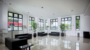 A spacious, modern living room with large windows, black sofas, and potted plants. - Cathayana Hotel (Kuantan)