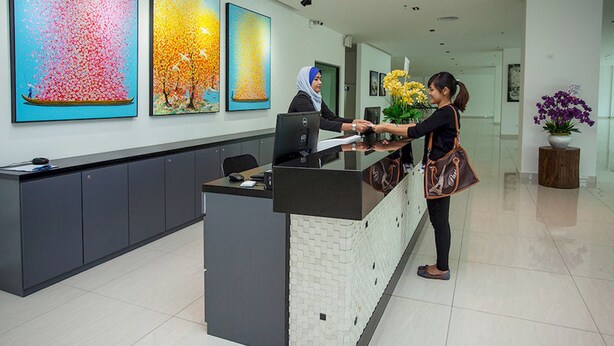A reception desk with a modern design, featuring a black and white tiled counter and a computer monitor. - Cathayana Hotel (Kuantan)
