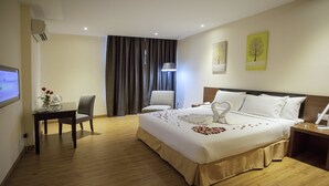 A hotel room with a large bed, a desk with a chair, a TV, and a window with curtains. - Cathayana Hotel (Kuantan)