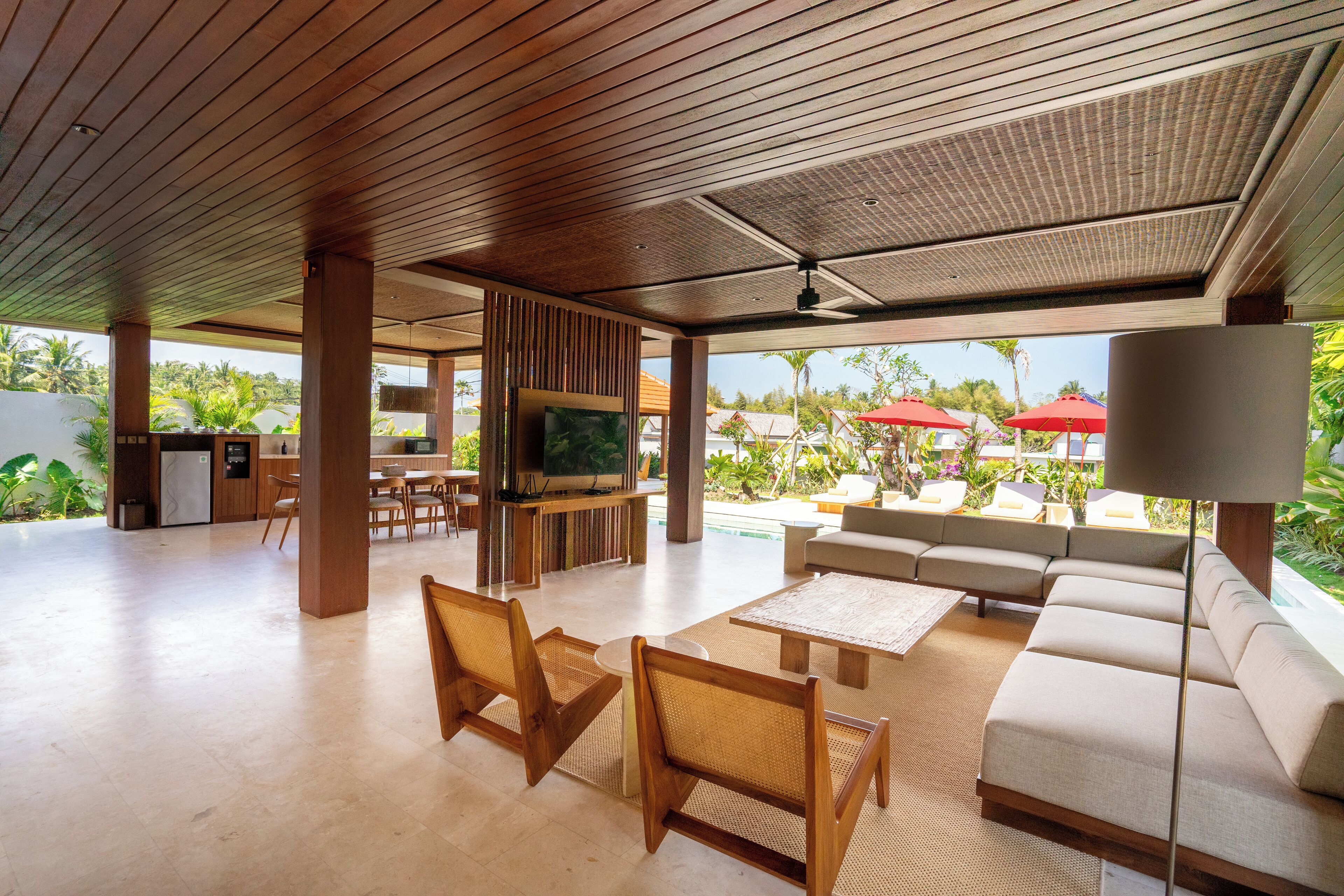 Un amplio salón con techo de madera, un sofá, un televisor y vistas a la piscina.