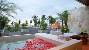 Un espacio de spa con una bañera de hidromasaje, asientos y vistas a la playa.