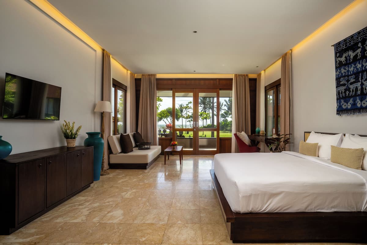 Quarto de hotel moderno com uma cama grande, um sofá, uma TV e uma varanda com vista.