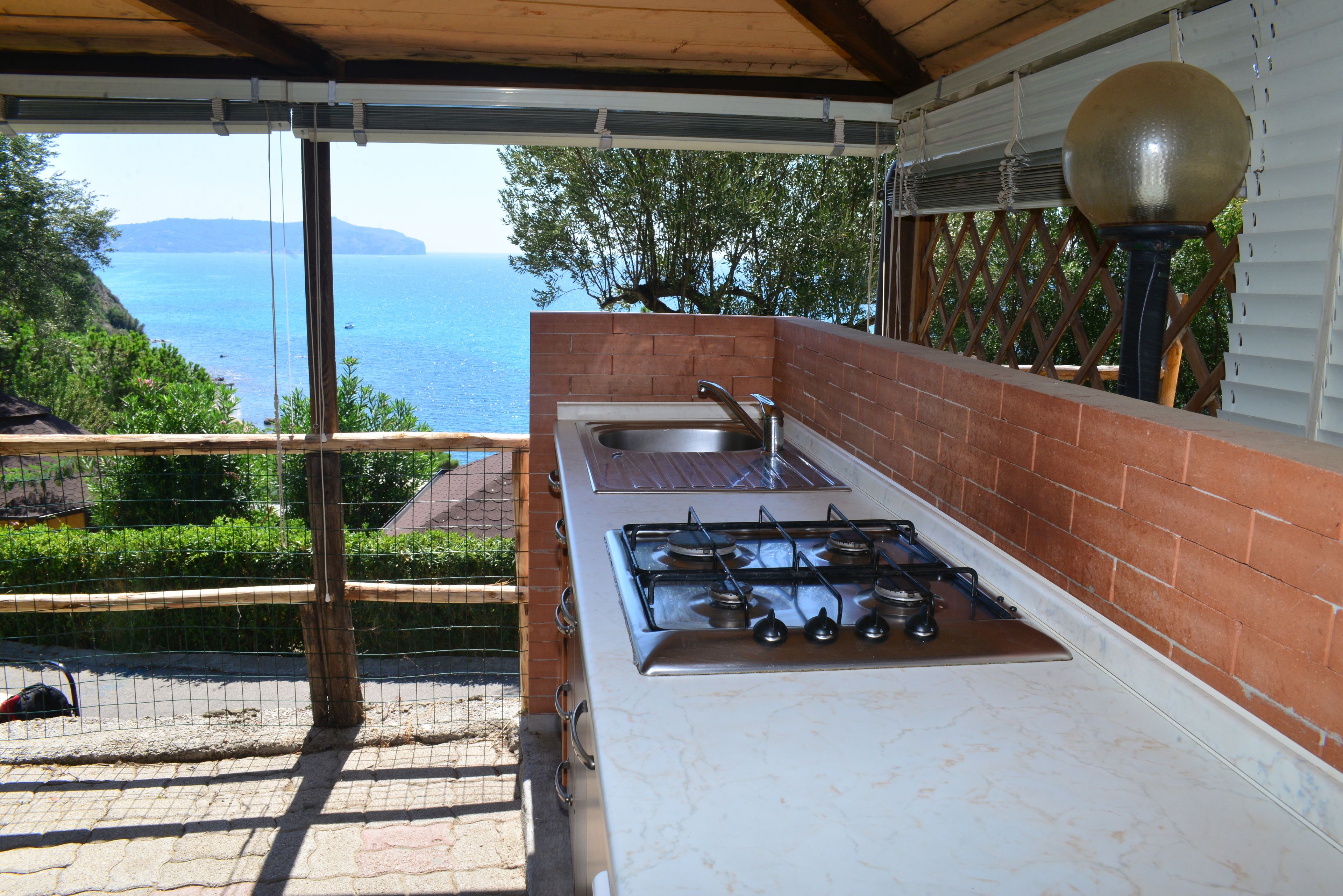 A compact kitchen with a gas stove, sink, and a view of the sea.