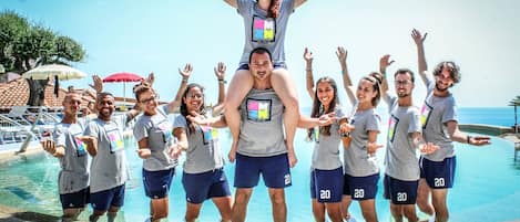 Un grupo de personas junto a una piscina con vistas claras al mar.