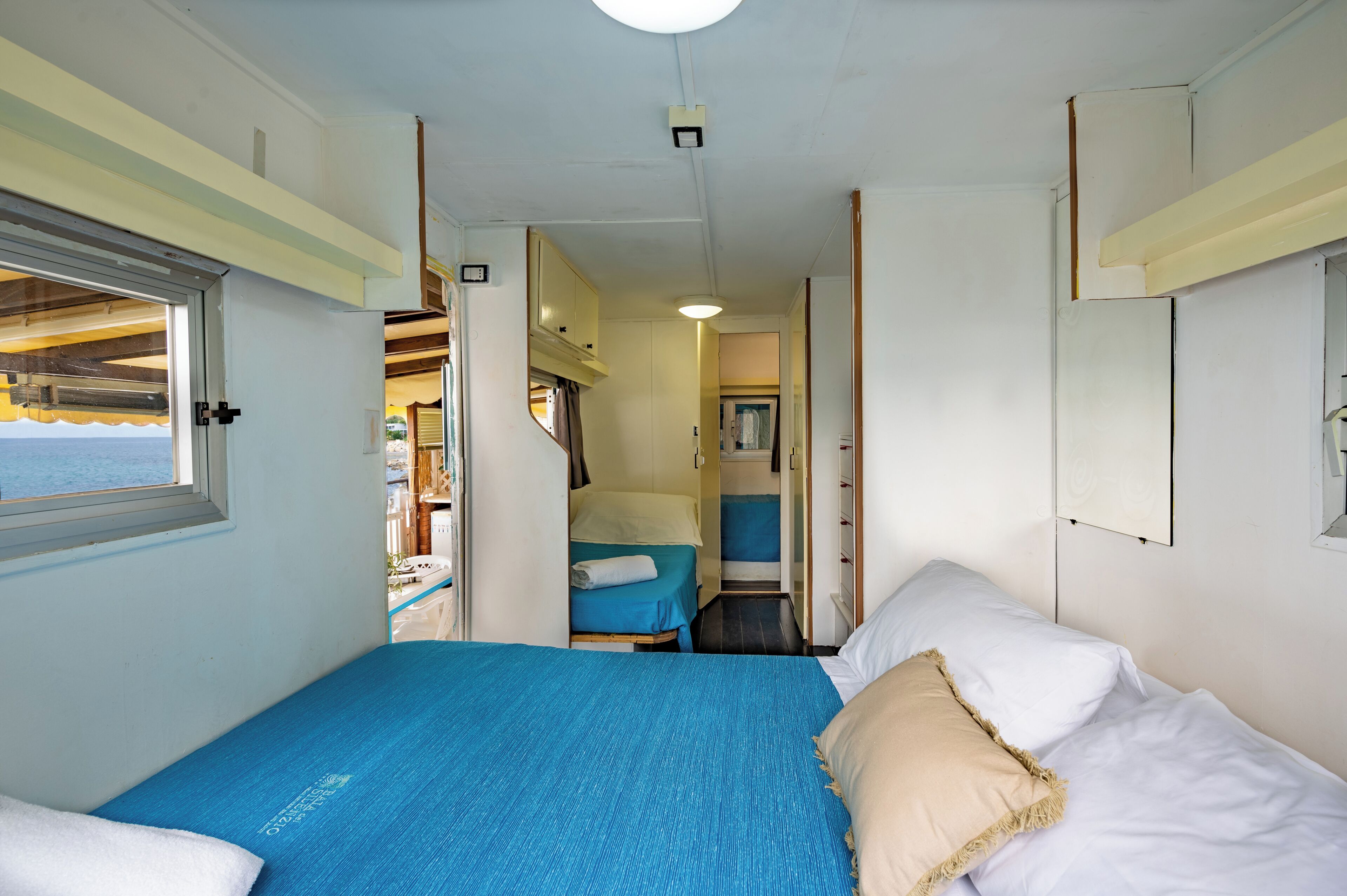 A compact room with a bed, a small table, and a window overlooking a scenic view.