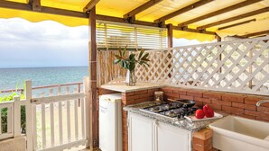 Une cuisine avec vue sur la mer, une clôture blanche et une pergola en bois.