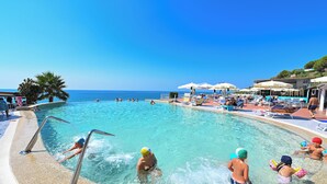 Une piscine à l’eau d’un bleu cristallin, entourée de chaises longues et de parasols.