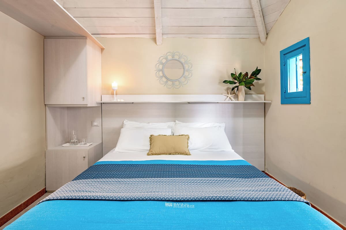 Ein ordentlich eingerichtetes Schlafzimmer mit Bett, Nachttisch und einem dekorativen Spiegel an der Wand.