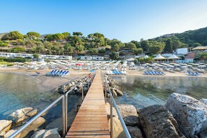 A wooden pier leading to a beach with rows of sun loungers and umbrellas. - Resort Baia del Silenzio (Pisciotta)