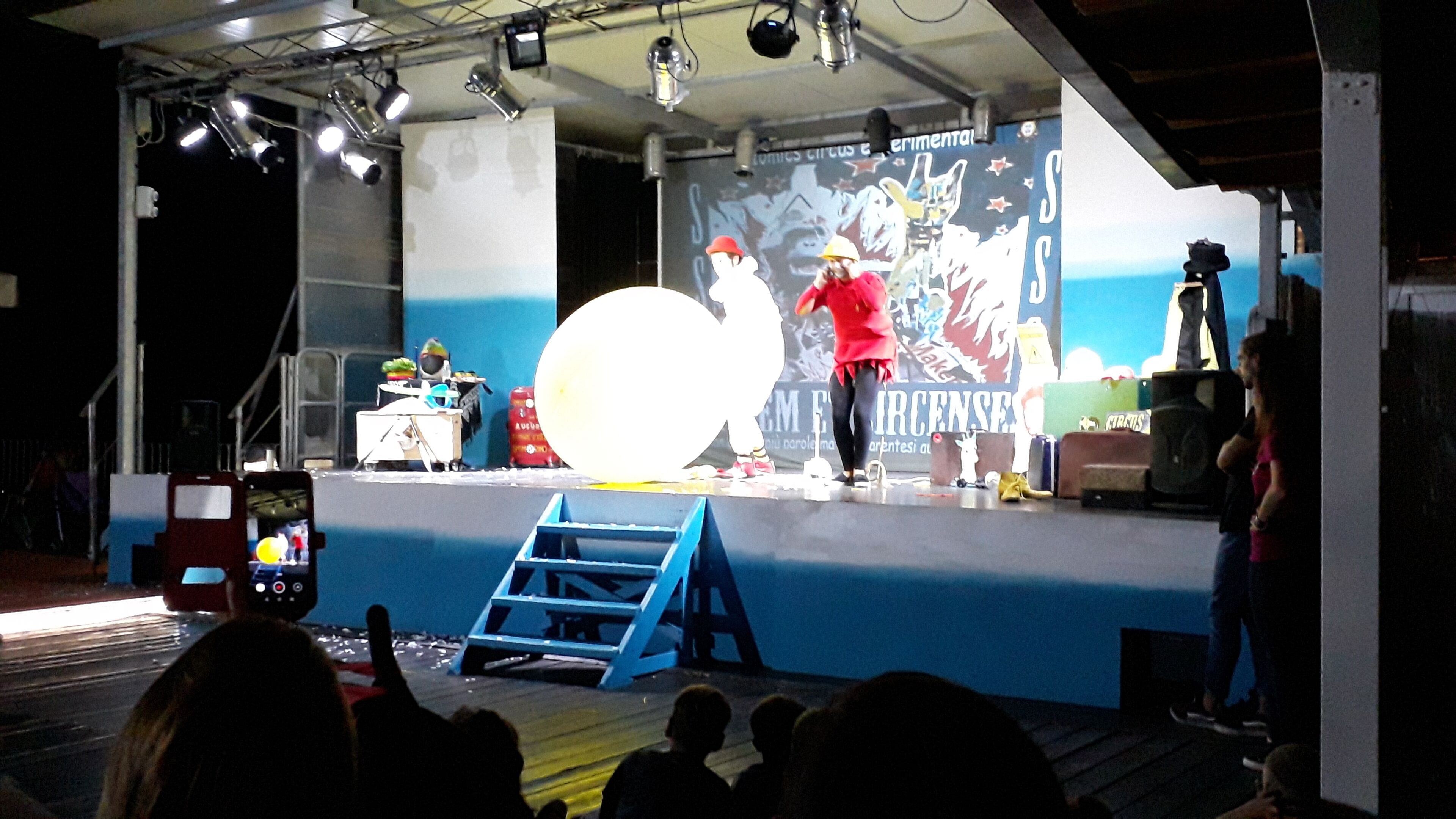 A stage with a large white backdrop, a ladder, and various props.