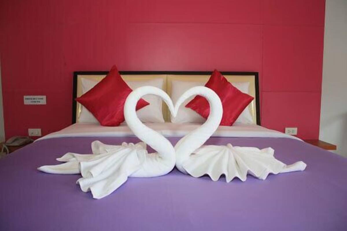 Ein Bett mit einer violetten Tagesdecke und zwei roten Kissen.