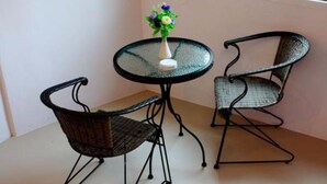 A small round table with a glass top and two wicker chairs with metal frames. - At Lamai Resort (Koh Samui)