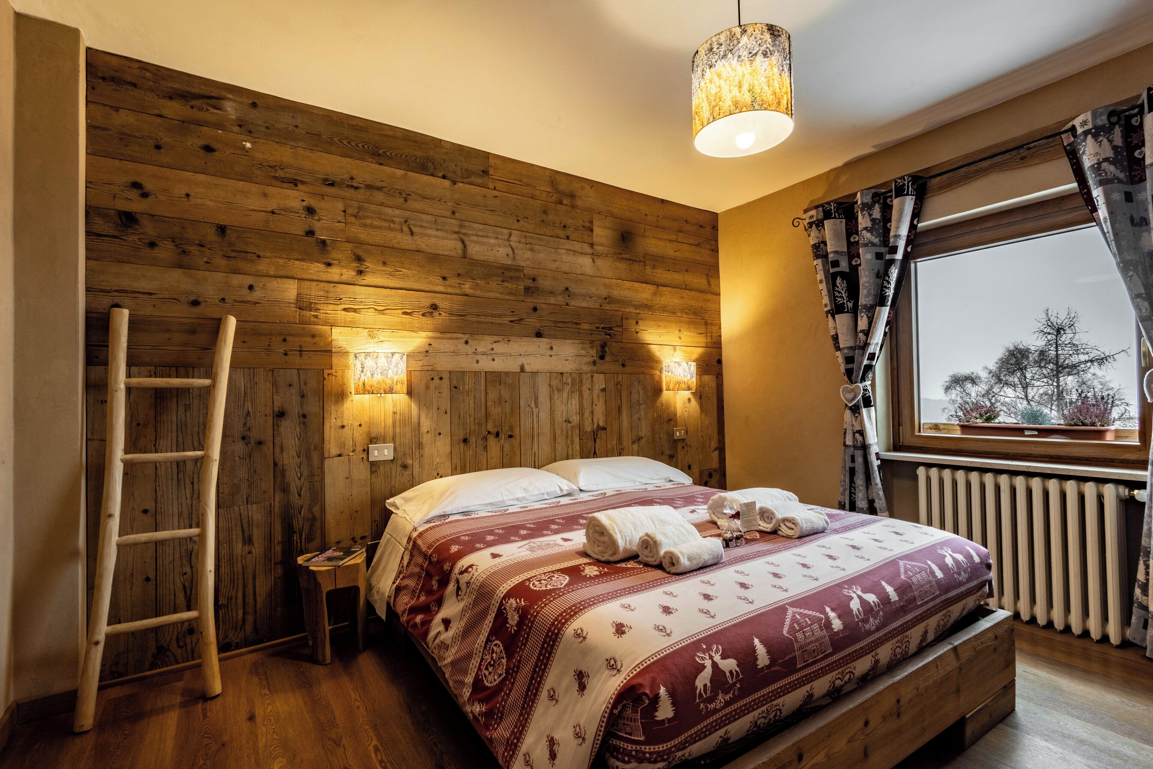 Camera da letto con rivestimento in legno, un letto, una scala e una finestra con tende.