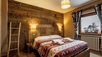 Camera da letto con rivestimento in legno, un letto, una scala e una finestra con tende.
