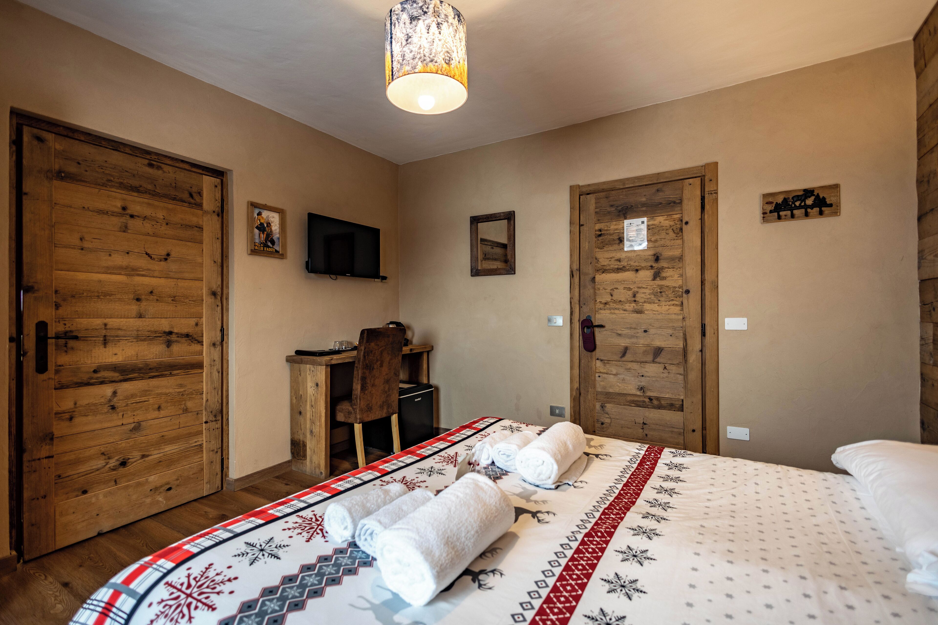 Una habitación con una cama, puertas de madera, un escritorio y una silla.
