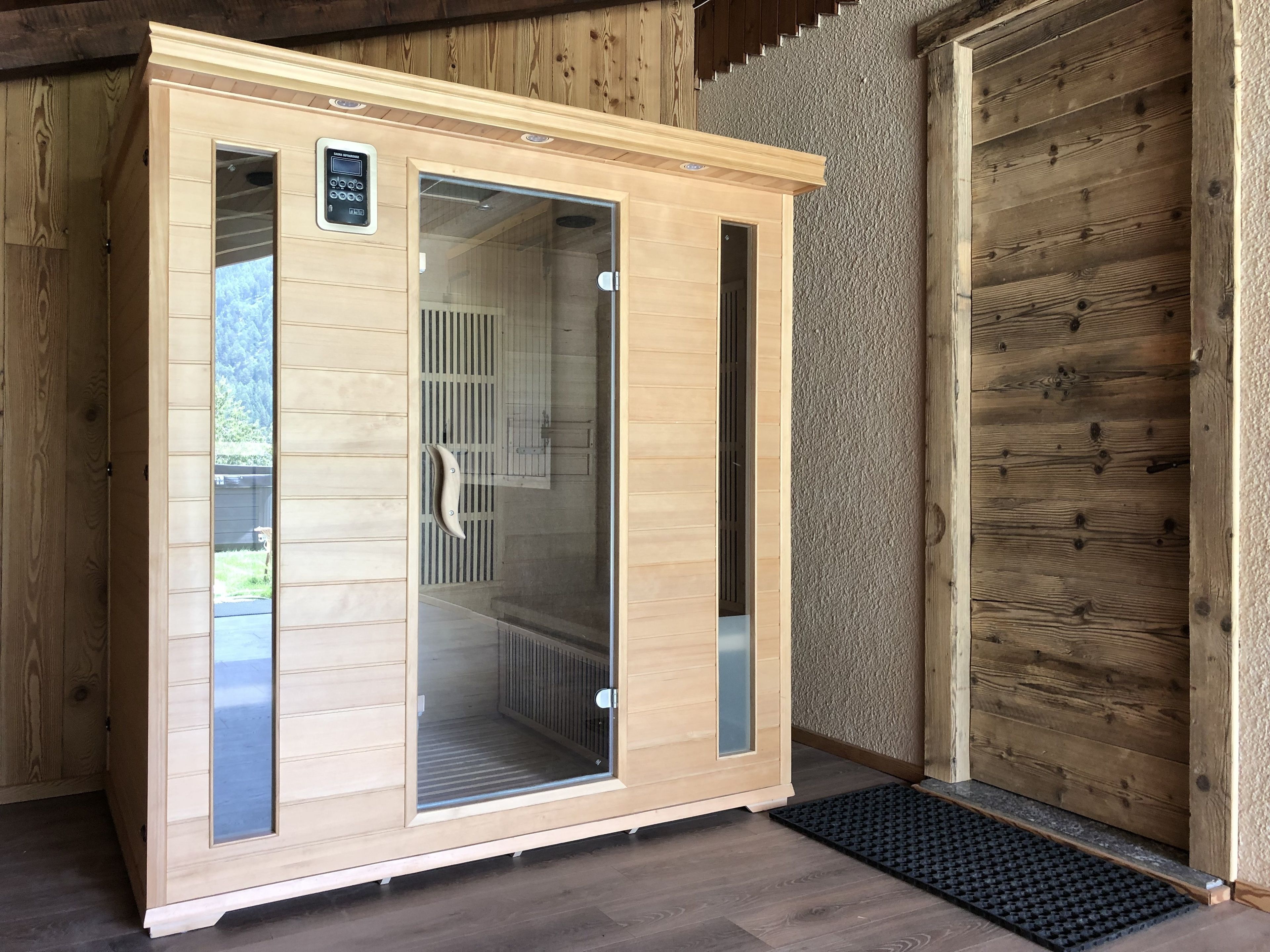 A sauna with a wooden exterior, glass doors, and a control panel on the left.