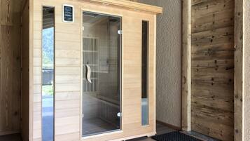 A sauna with a wooden exterior, glass doors, and a control panel on the left.