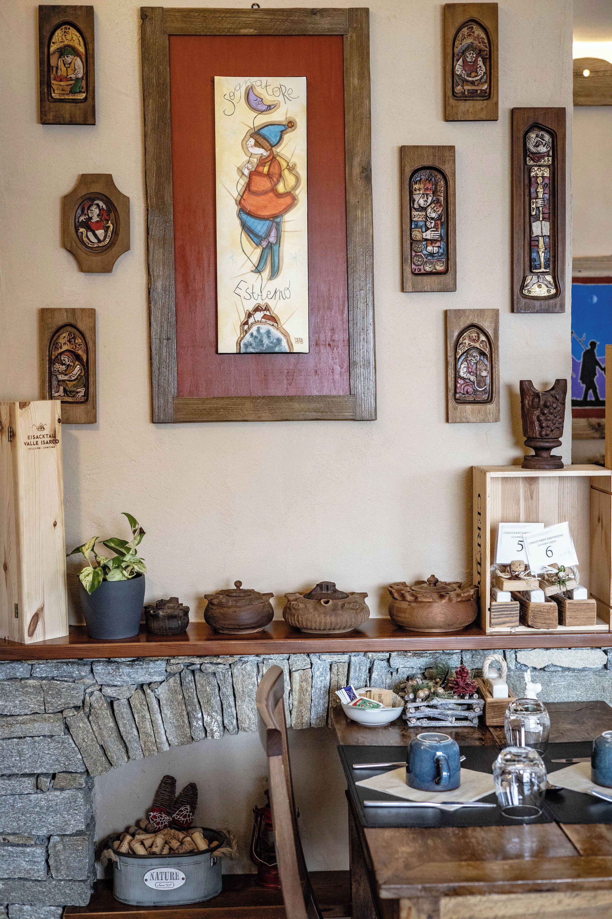 Un intérieur rustique agrémenté de décorations murales en bois, d’une cheminée en pierre et d’un comptoir en bois sur lequel sont disposés des bocaux et une plante.