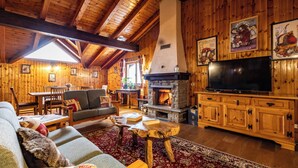 Interior acogedor de una cabaña de madera con chimenea, muebles de madera y un televisor.