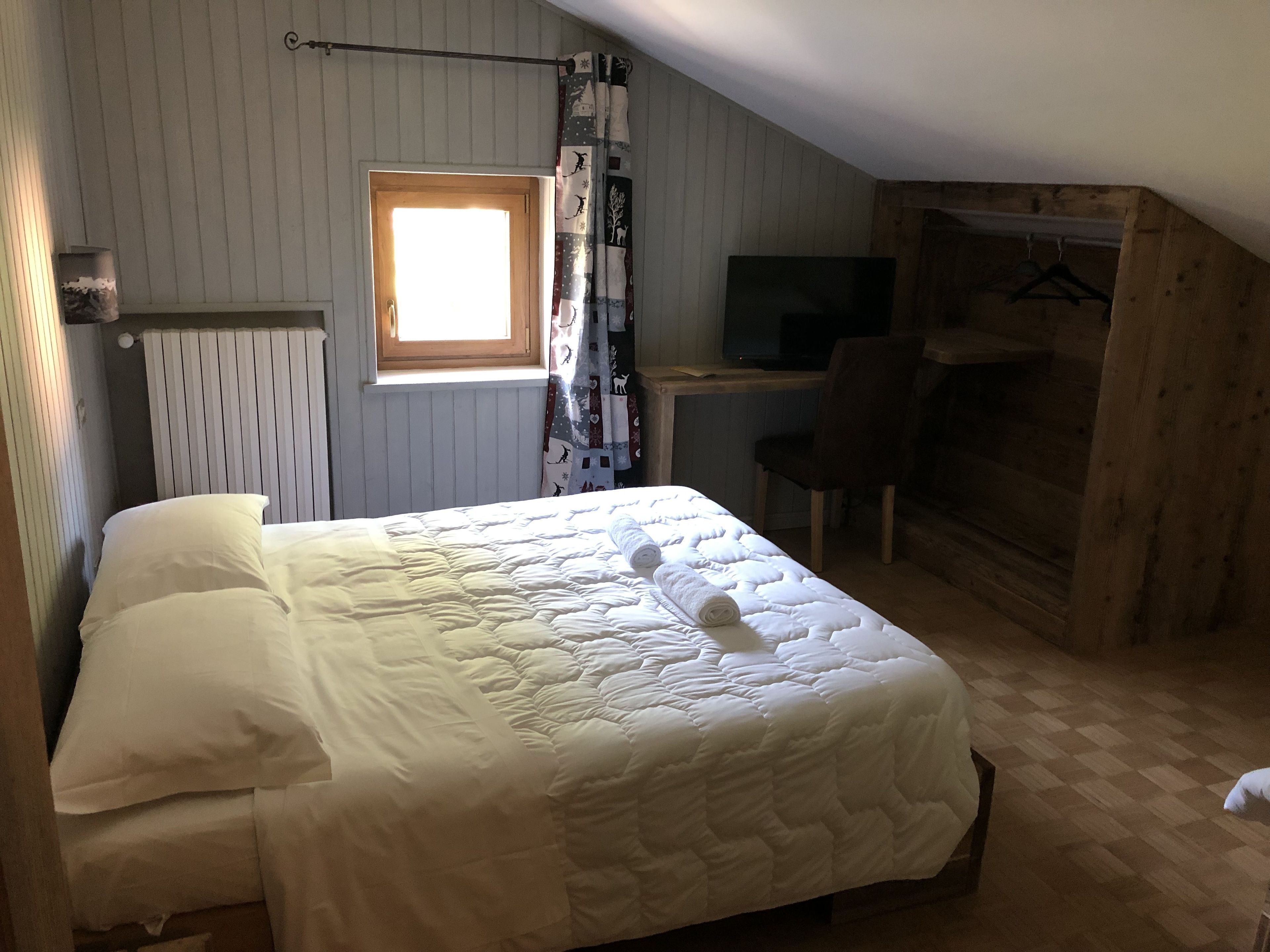 Un dormitorio con cama, escritorio y silla.