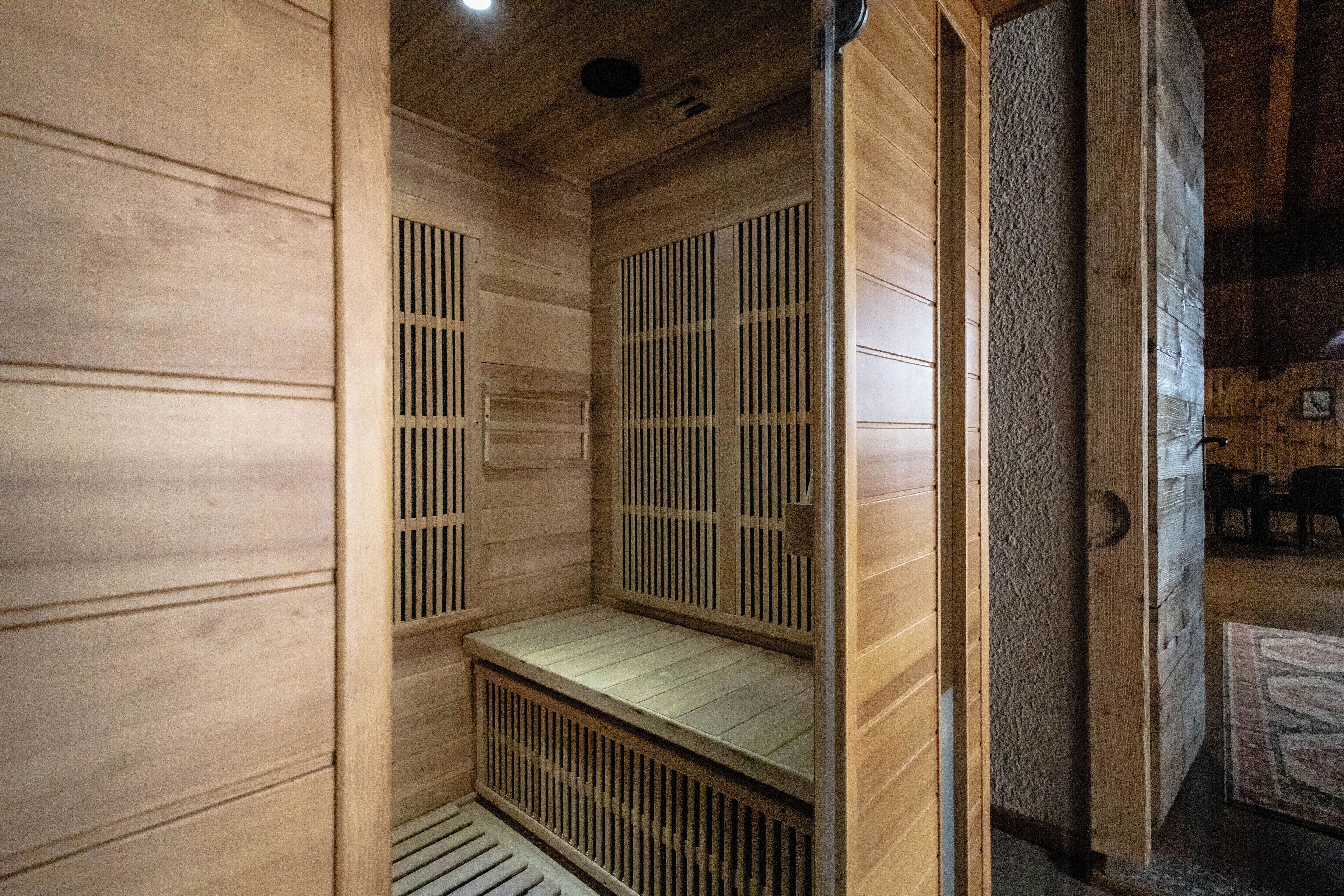 Una sauna de madera con un banco y una puerta.