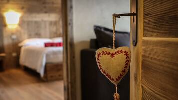 A heart-shaped hanging decoration with tassels, a wooden door, and a bed with a white blanket and red pillow in the background.