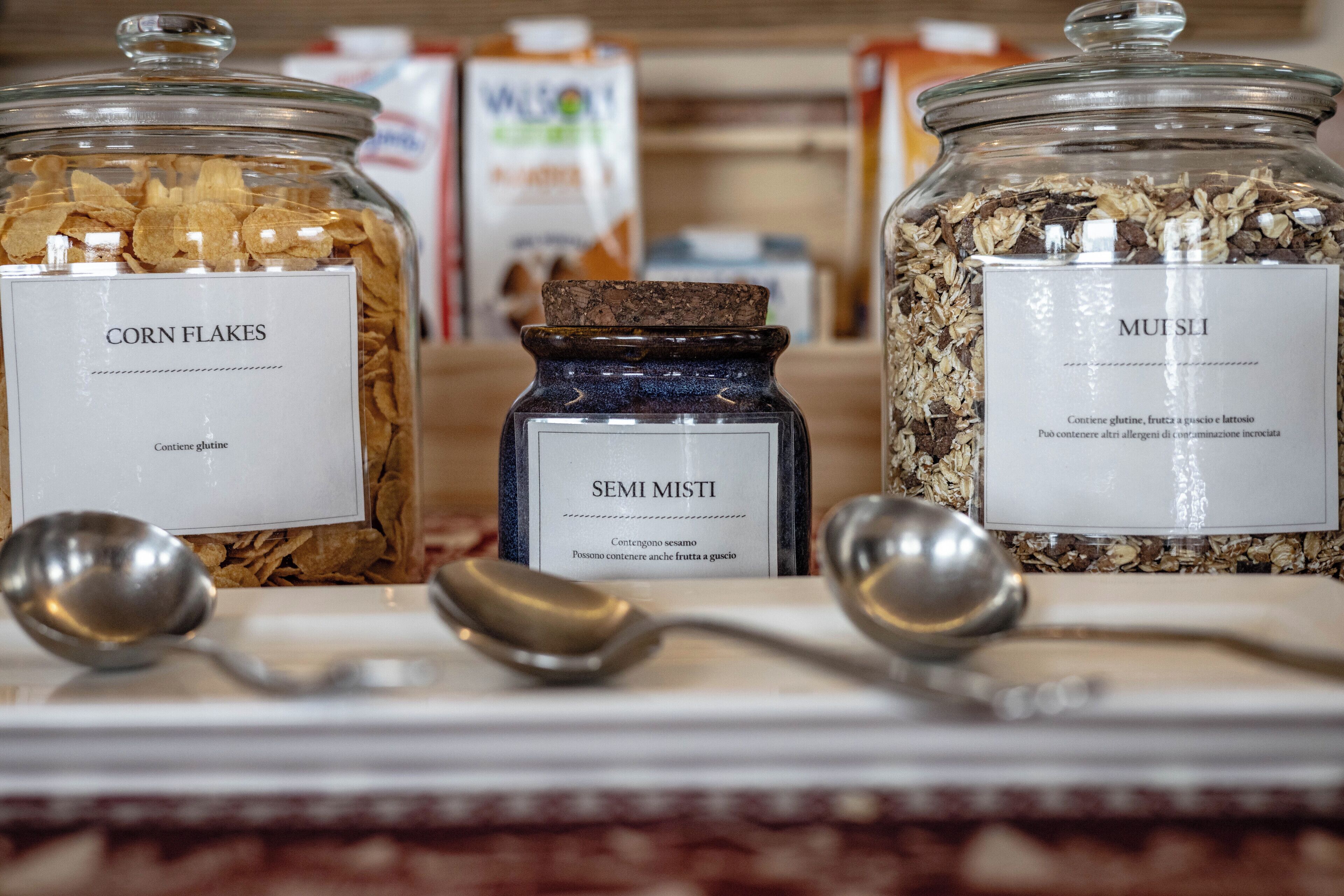 Tres frascos de vidrio etiquetados con distintos tipos de cereal en un estante.