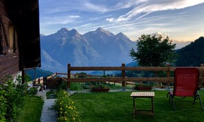 Terraza de madera con banco y mesa, con vista a un paisaje montañoso.