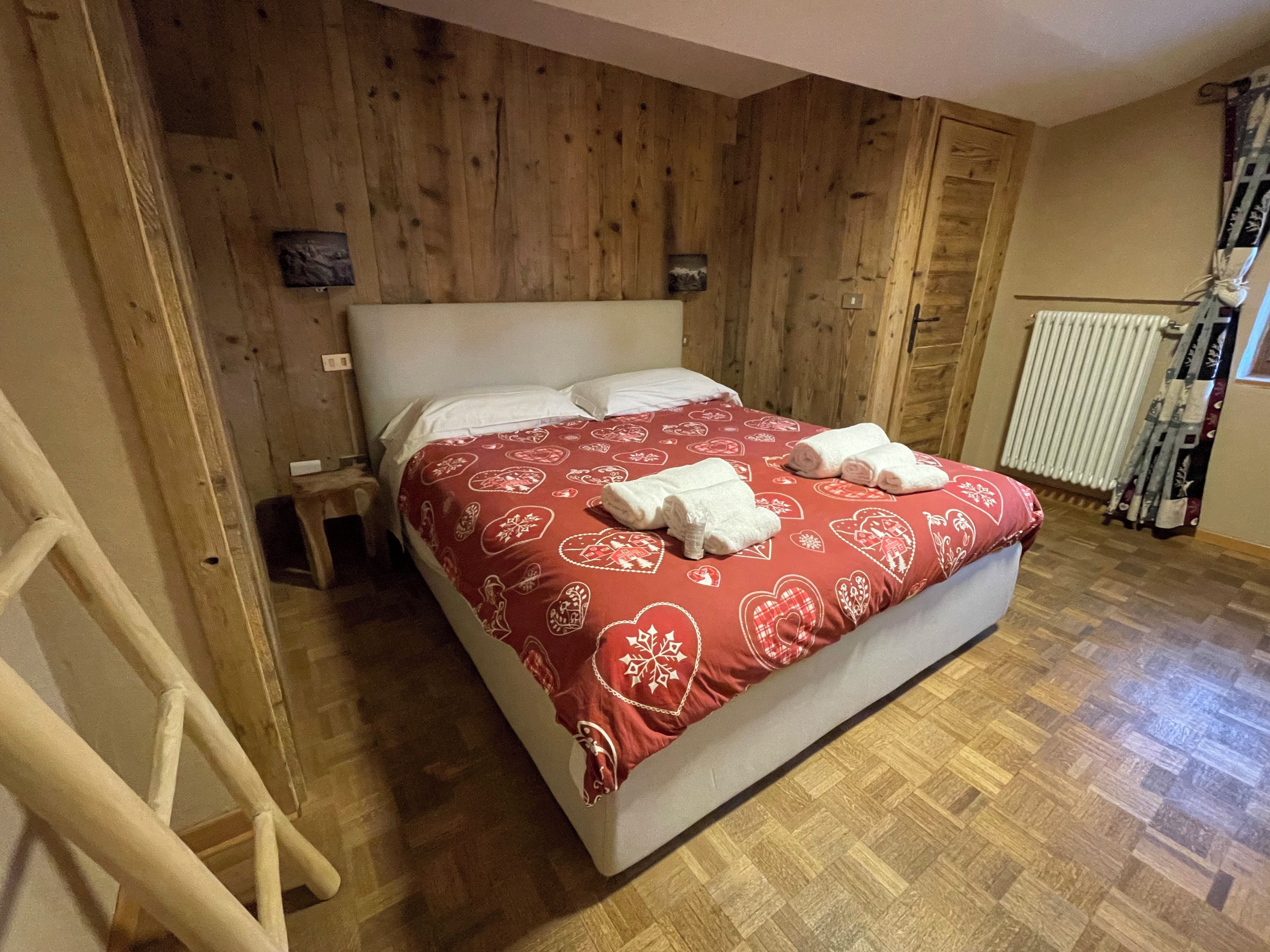 Una habitación con paneles de madera, una cama, una escalera y un radiador.
