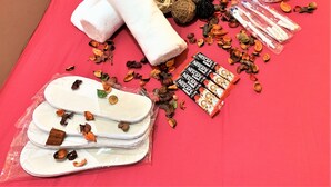 Una mesa con mantel rojo, con artículos de aseo, una planta y adornos.