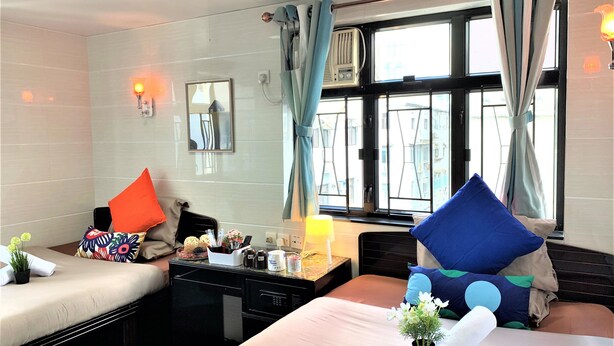 Habitación de hotel con dos camas, una mesita con lámpara, un espejo y una ventana con cortinas.