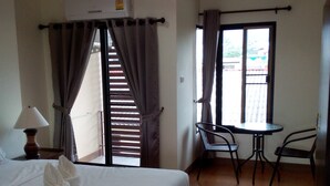 A hotel room with a bed, a table with chairs, a window with curtains, and a ceiling light. - Chiang Mai P Place - Adults Only (Chiang Mai)