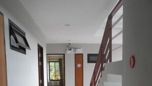 A hallway with a polished floor, a wooden door, and a staircase with a wooden railing. - Chiang Mai P Place - Adults Only (Chiang Mai)