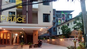 A building with a sign that reads "PLACE" in English and another language. There are potted plants and a person sitting at a table outside. - Chiang Mai P Place - Adults Only (Chiang Mai)