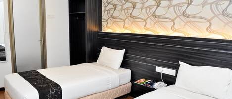 Une chambre d’hôtel avec deux lits, une armoire, un mur décoré de motifs et une table de chevet avec un téléphone.