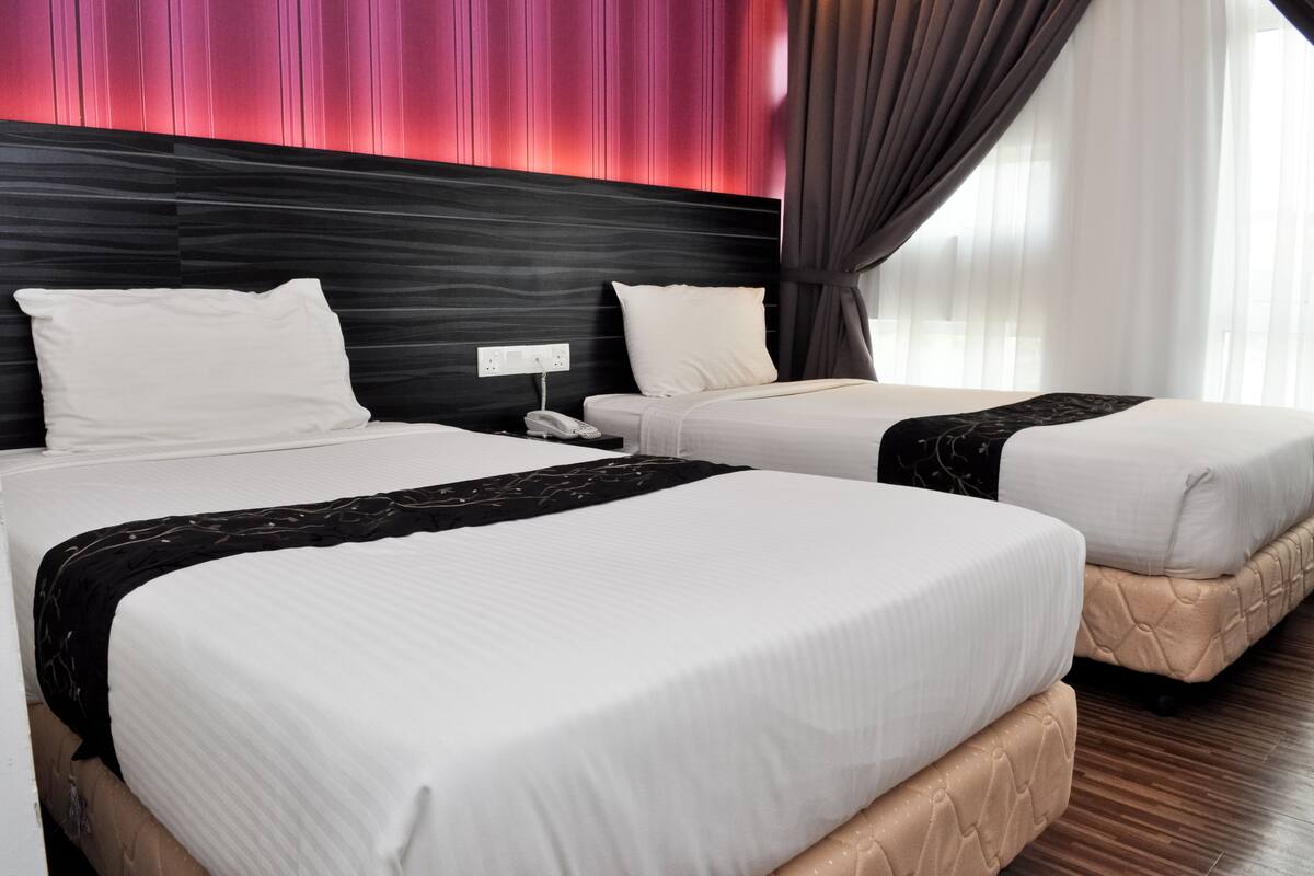 Quarto de hotel com duas camas, uma cabeceira moderna e vista para a cidade.