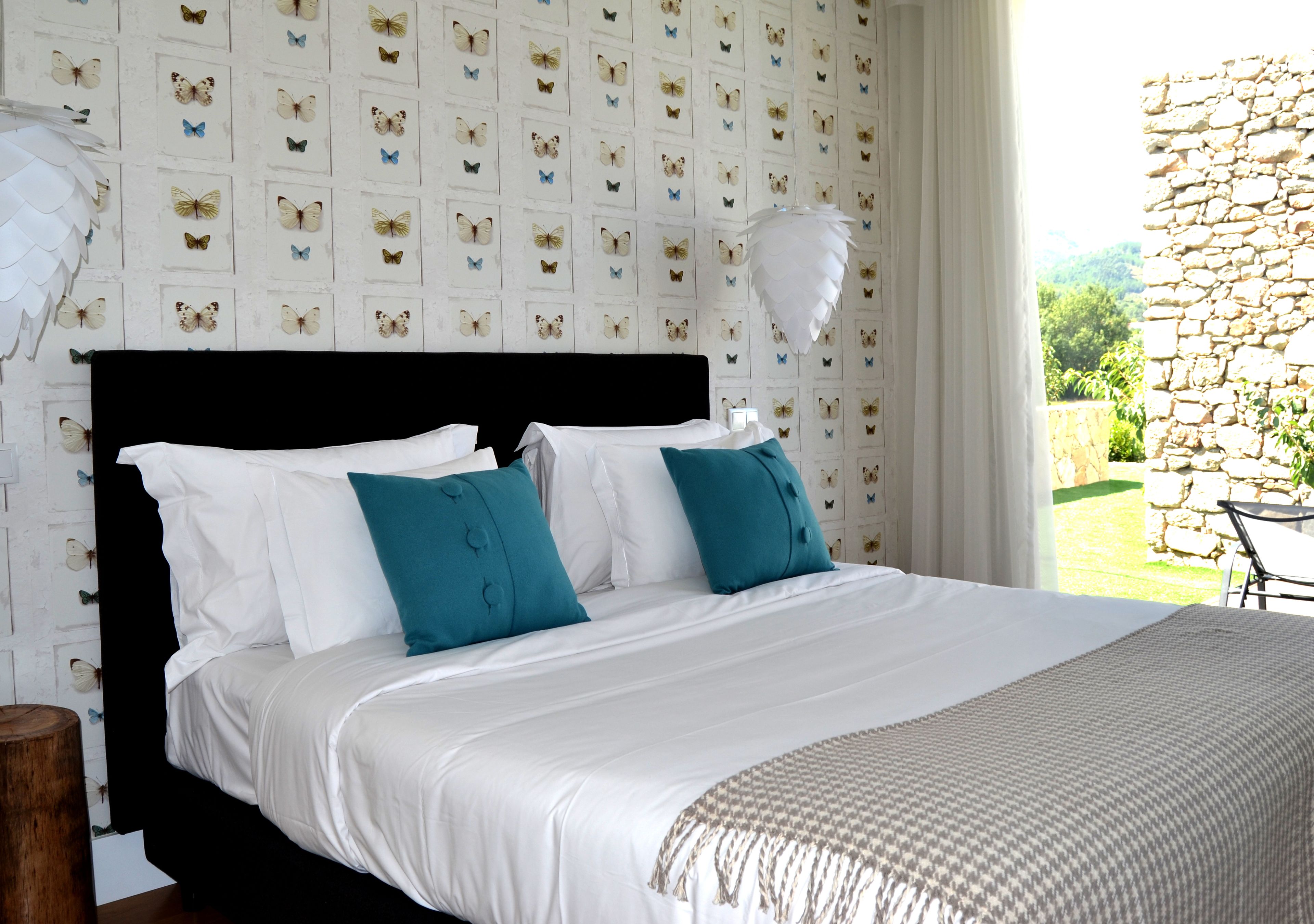A bedroom with a bed, white bedding, and a butterfly-patterned wall.